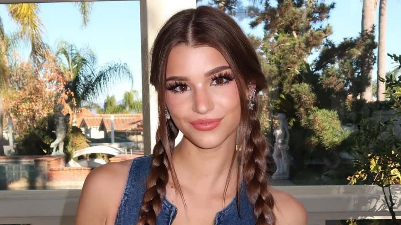 Brooke Monk effortlessly pairs a trendy denim zip-front top with playful braided pigtails for a fresh, Y2K-inspired casual look.
