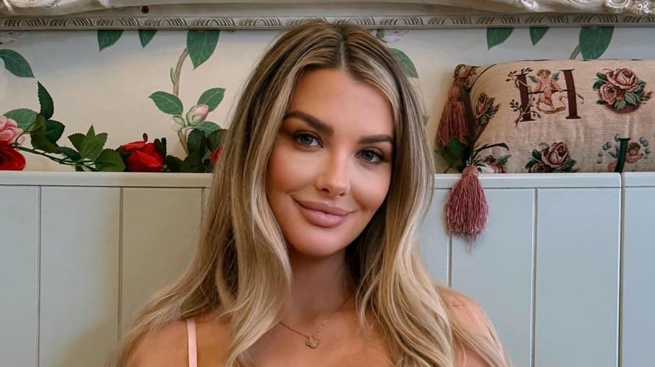 Emily Sears's light blonde waves and delicate gold necklace perfectly exemplify an effortless, sophisticated approach to beauty that is both timeless and chic.