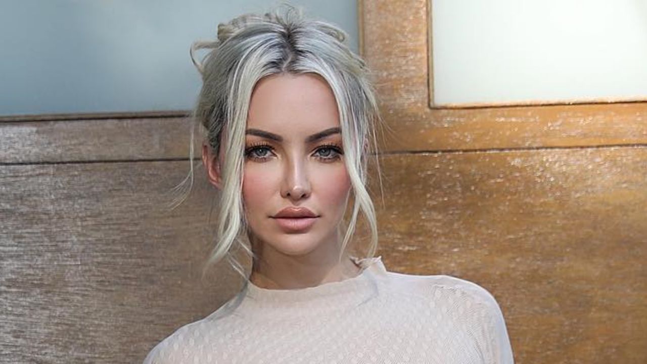 Lindsey Pelas effortlessly balances modern minimalist elegance with a chic, high-neck textured top complemented by soft neutral makeup and a relaxed, tendril-framed updo.