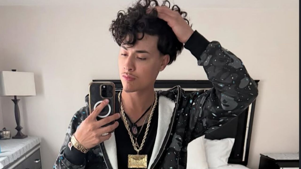 Alex Chino showcases an effortlessly cool streetwear aesthetic by accessorizing a unique patterned hoodie with a bold collection of layered gold chains.
