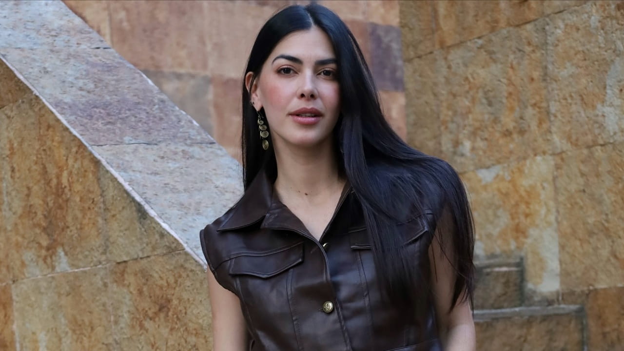 Ariana Dugarte delivers a bold masterclass in contemporary street style by pairing a tailored, sleeveless dark brown faux-leather top with subtle metallic drop earrings.