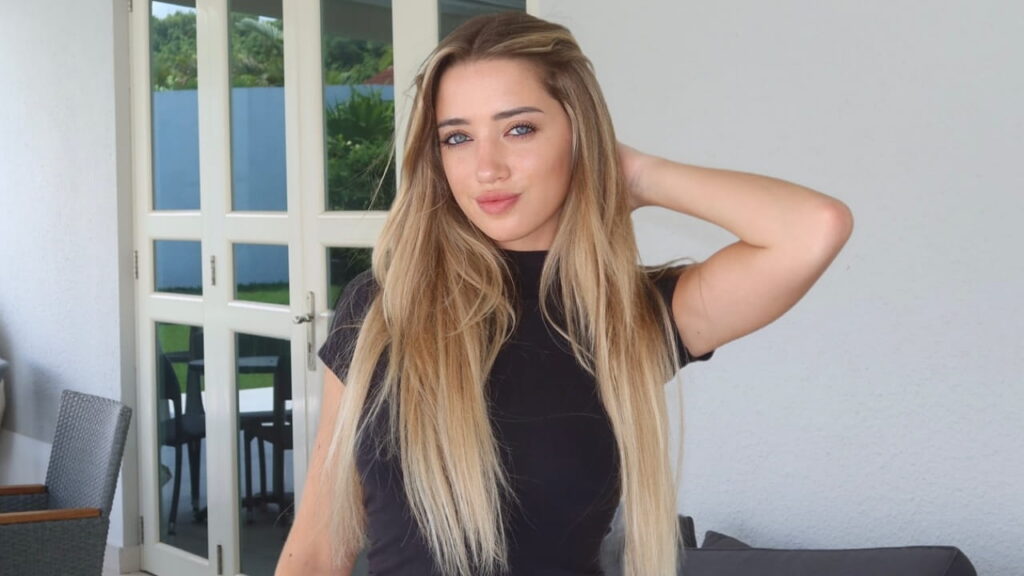 Ashley Carter channels clean, minimalist chic in a classic fitted black crewneck top, effortlessly complemented by long sun-kissed tresses and radiant daytime makeup.