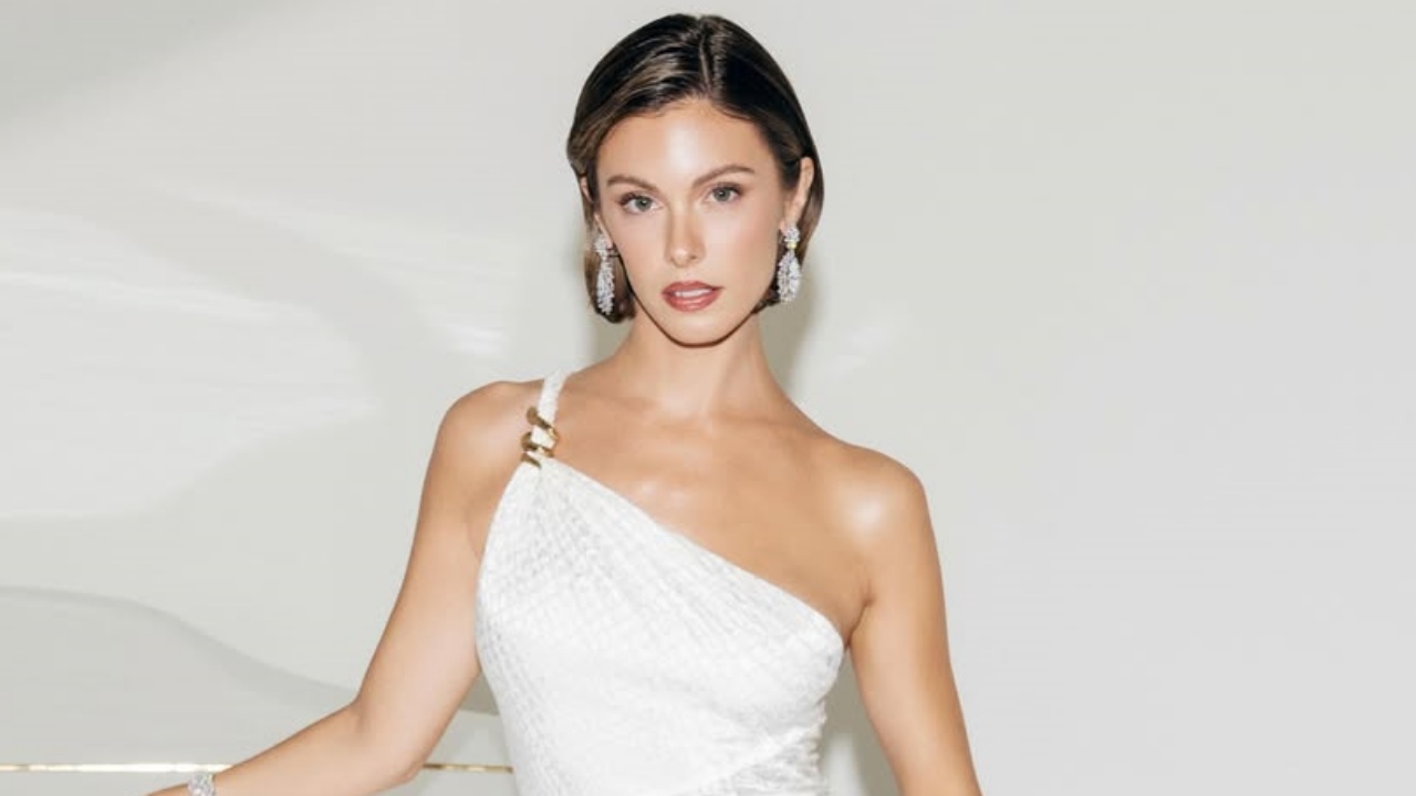 Carmella Rose epitomizes sophisticated red-carpet glamour in an asymmetric one-shoulder white gown accented with subtle gold hardware and statement crystal earrings.