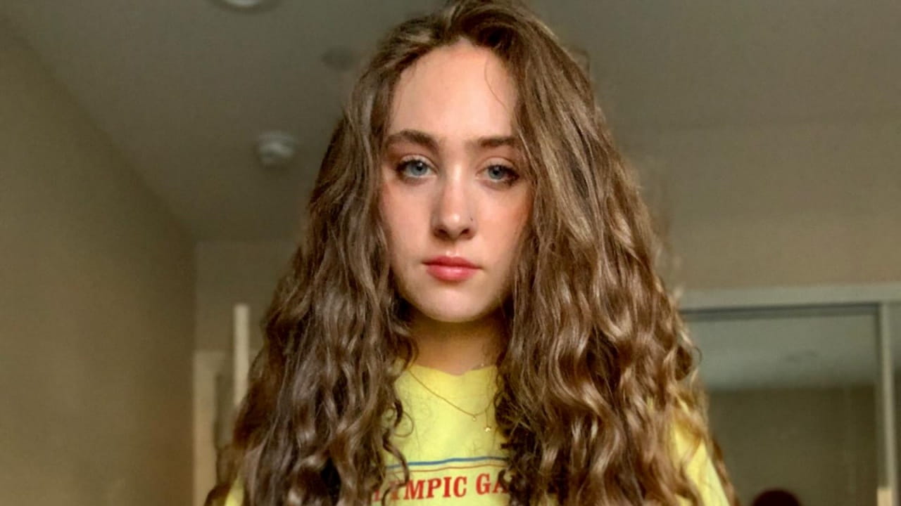 Chappell Roan embraces a relaxed, effortless everyday aesthetic, pairing a vintage-inspired yellow graphic tee with voluminous natural curls and subtle gold jewelry.