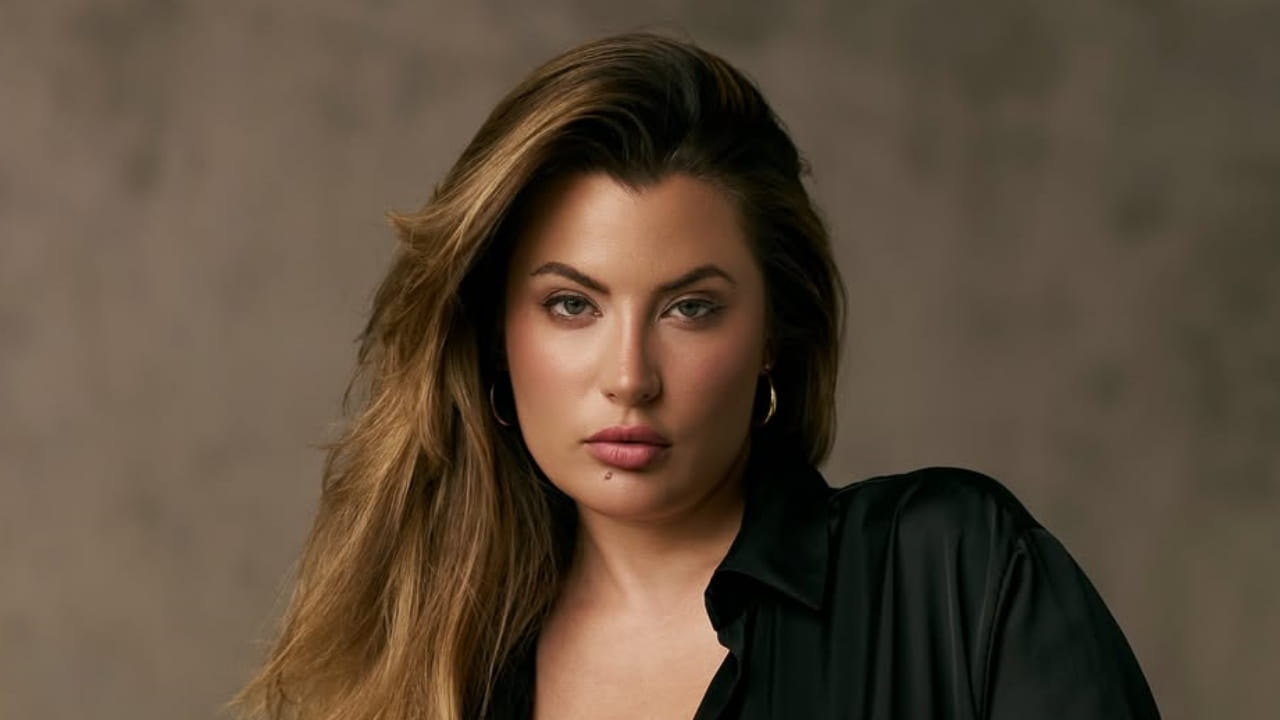 Cherie Noel embraces effortless luxury in a classic black satin button-down shirt accessorized with understated gold hoop earrings for a polished, modern look.