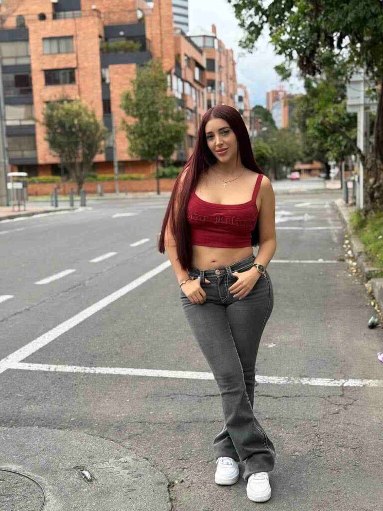 Embracing a classic Y2K street style vibe, Jessica Sodi pairs a cropped burgundy tank top with contrast-stitched flare jeans and fresh white sneakers.