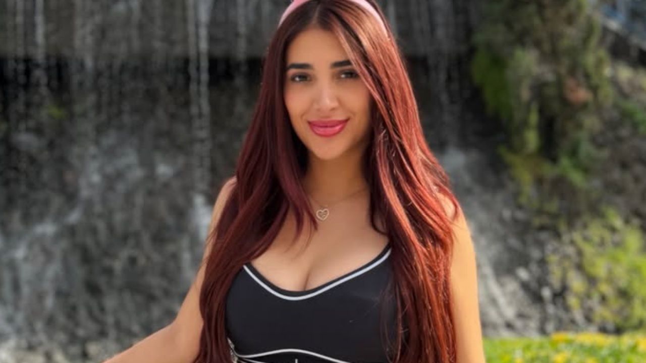 Jessica Sodi channels an effortless sporty-chic aesthetic, pairing a contrast-piped black athleisure top with a playful pink headband and subtle gold jewelry.