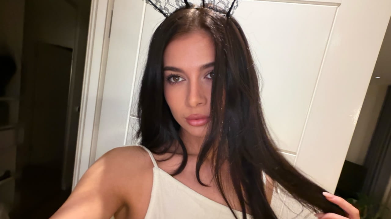 Kiera Lee channels playful evening glam by pairing a delicate cream strap top with an intricate black lace crown headband and effortless soft waves.