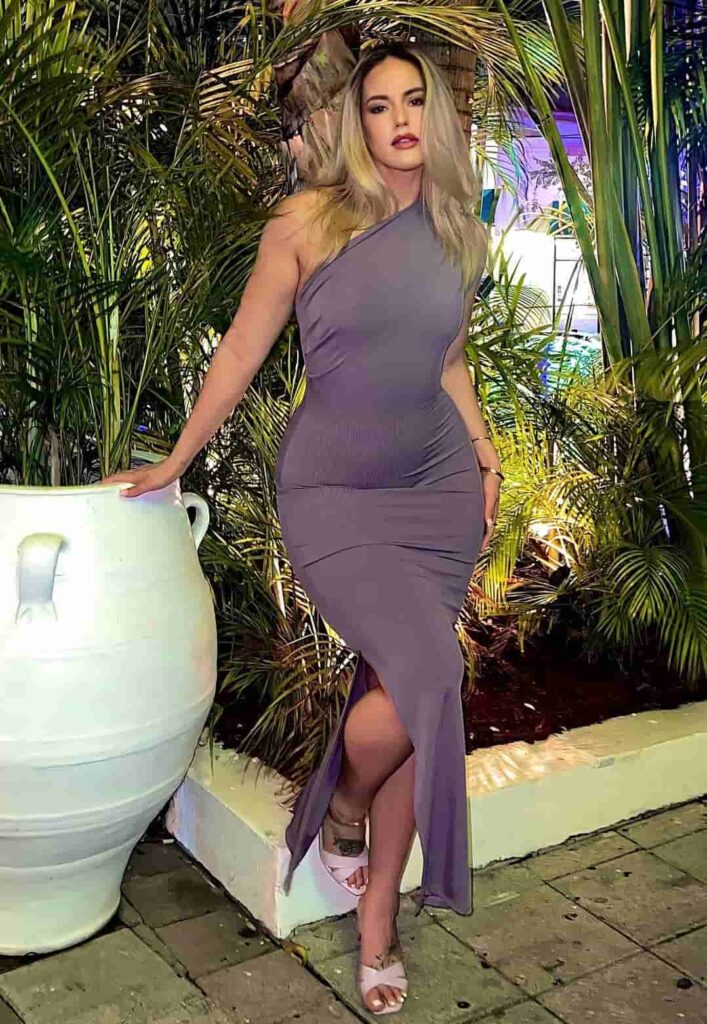 Marissa DuBois stuns in a muted slate-grey one-shoulder bodycon dress with a graceful side slit, perfectly styled with pastel open-toe heels for an elegant resort evening look.