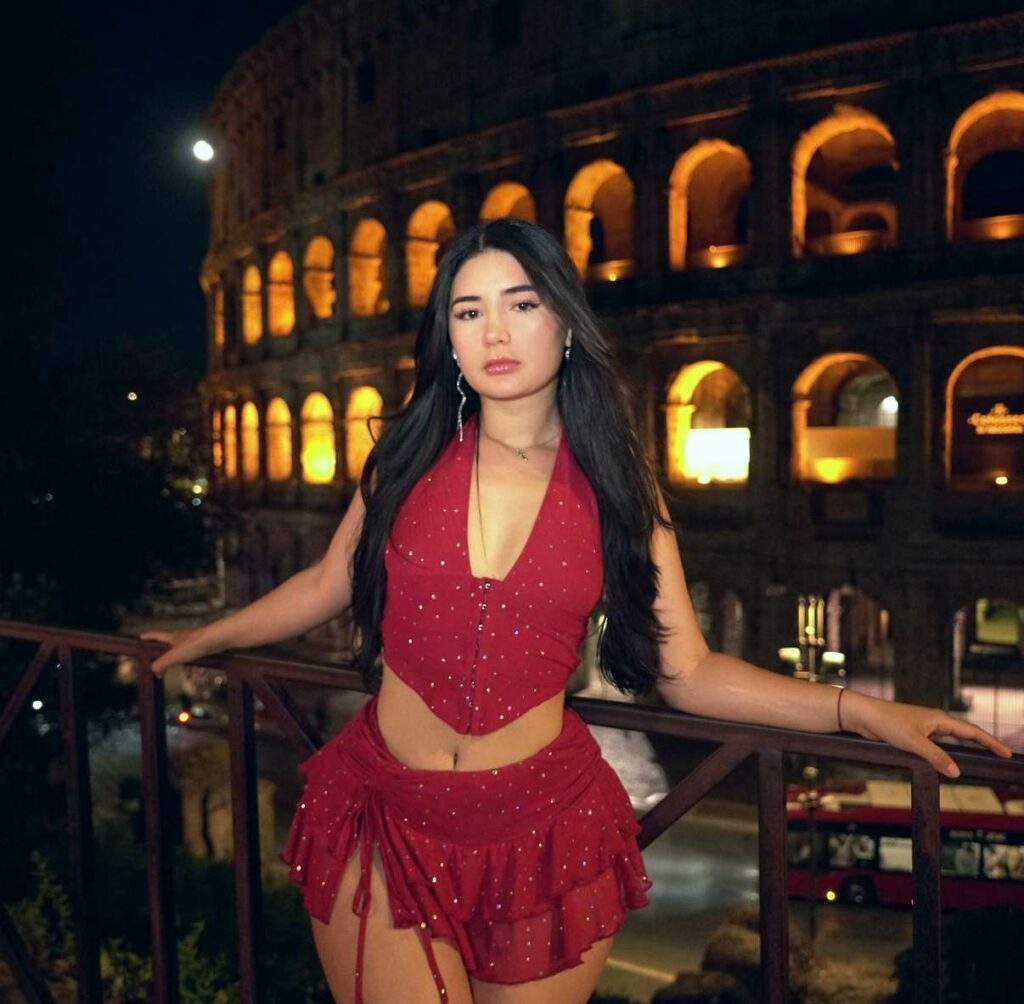 Nicole Delgado brings vibrant nightlife style to Rome with a dazzling red crystal-embellished halter crop top and tiered ruffled skirt set overlooking the historic Colosseum.