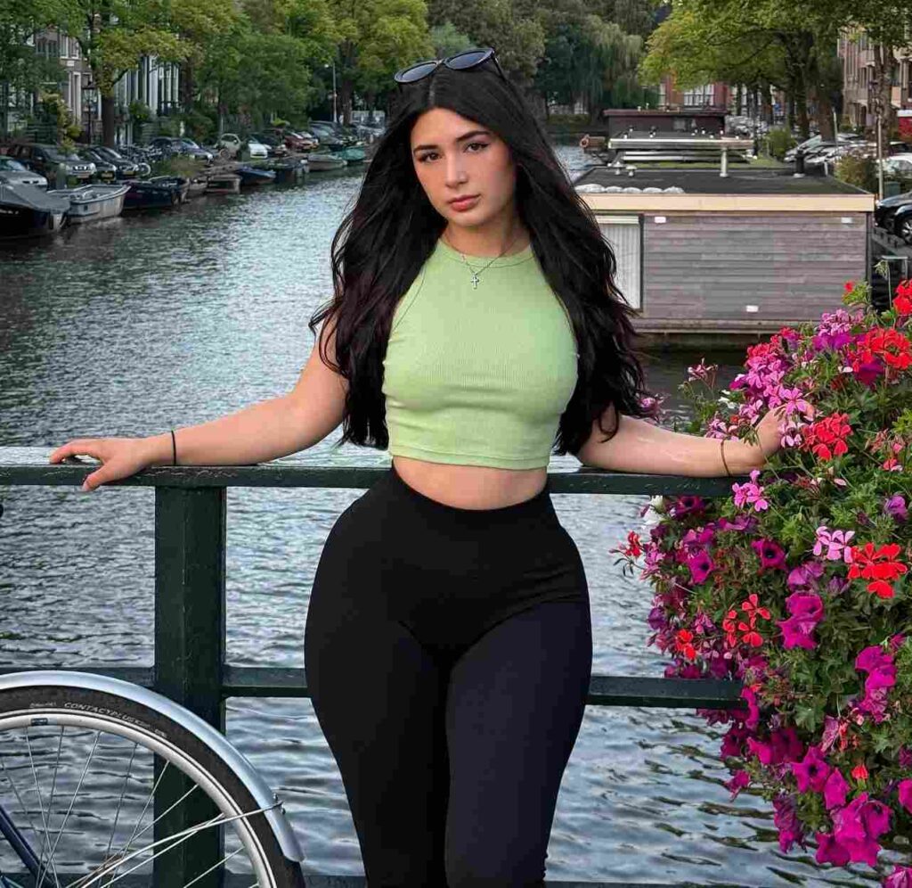 Nicole Delgado masters chic European vacation athleisure, styling a pastel green ribbed crop top with high-waisted black leggings against the picturesque backdrop of Amsterdam’s floral canals.