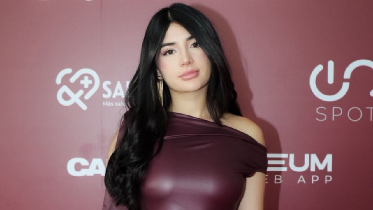 Nicole Delgado showcases polished red carpet glamour in a sculptural one-shoulder burgundy faux-leather dress accented with statement drop earrings and a radiant soft-glam makeup look.