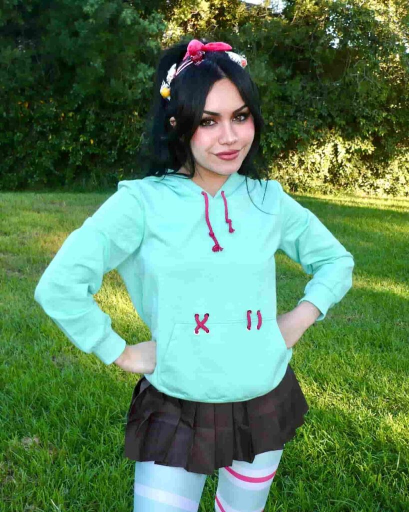 Tara Yummy delivers a playful, pop-culture-inspired ensemble featuring a mint green hoodie, a pleated mini skirt, and fun candy hair accessories for a vibrant streetwear aesthetic.
