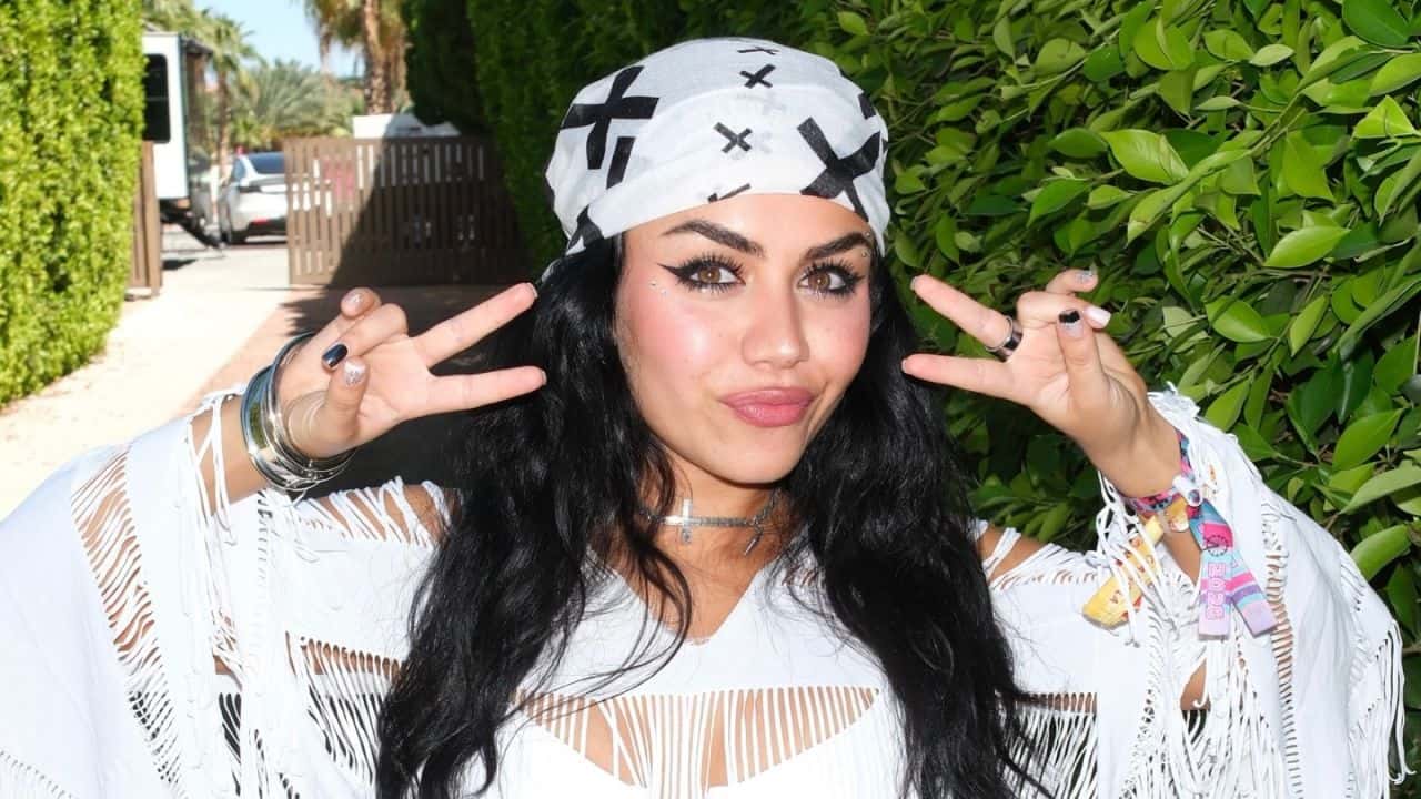 Tara Yummy effortlessly channels an edgy festival vibe by combining a graphic patterned bandana with textured fringe details and bold layered jewelry.