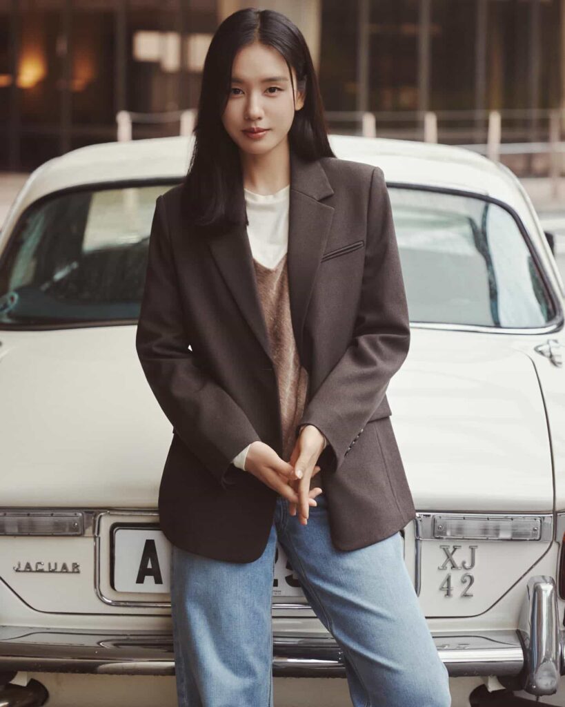 Channeling timeless smart-casual chic, Ahn Eun Jin layers an oversized espresso-toned blazer over a neutral knit vest and classic light-wash denim for a sophisticated vintage-inspired ensemble.