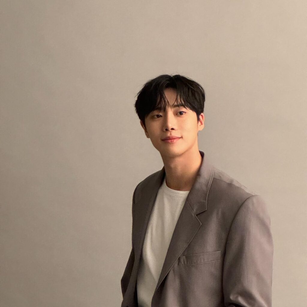 Exuding effortless smart-casual sophistication, Choo Young Woo pairs a soft-tailored taupe blazer with a crisp white crewneck for a clean, understated aesthetic.