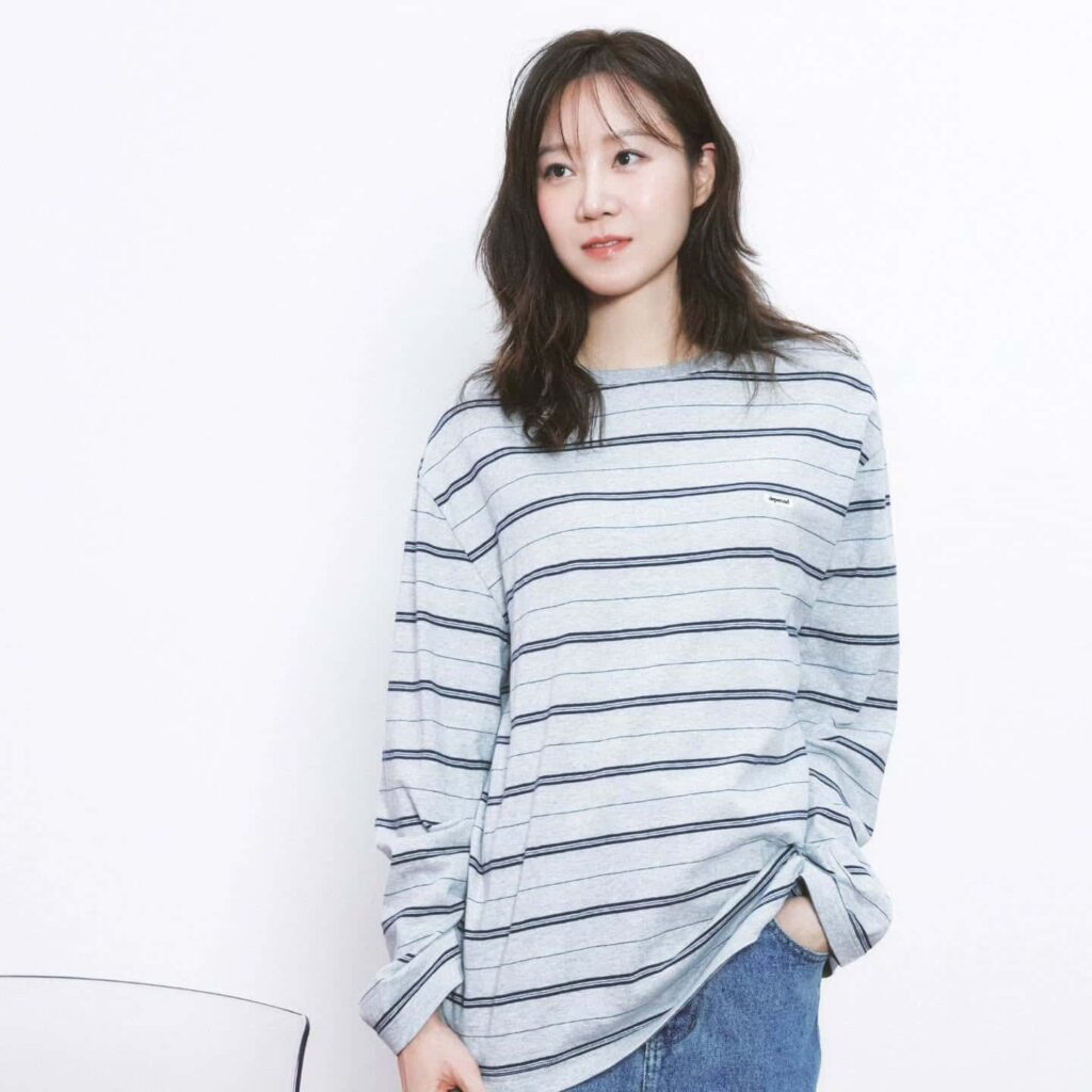 Embracing effortless style, Gong Hyo Jin rocks a relaxed, oversized striped long-sleeved shirt paired with classic light wash denim jeans for a cool and casual vibe.