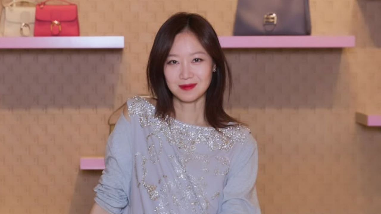 Dressed in an elegant lavender-grey silk blouse adorned with intricate silver embellishments, Gong Hyo Jin embodies sophisticated glamour in a luxurious boutique setting.