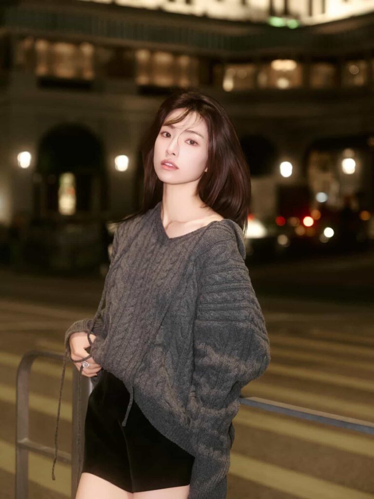 Capturing effortless nighttime street style, Ha Young pairs an oversized charcoal cable-knit sweater with sleek black shorts for a cozy yet sophisticated urban aesthetic.