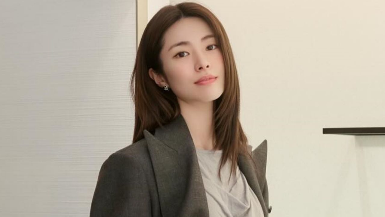 Ha Young effortlessly defines modern corporate chic, layering a sharply tailored charcoal blazer over a soft neutral drape top for an elegant, elevated business-casual look.