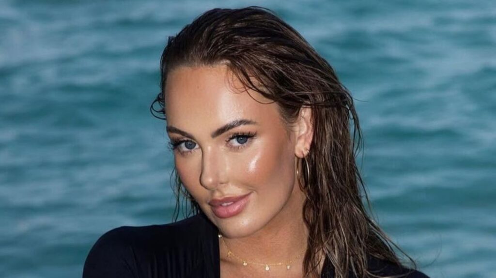 Honeyy Brooks effortlessly elevates functional seaside style by pairing a sleek black zip-up rashguard with a delicate gold drop necklace and classic hoop earrings.