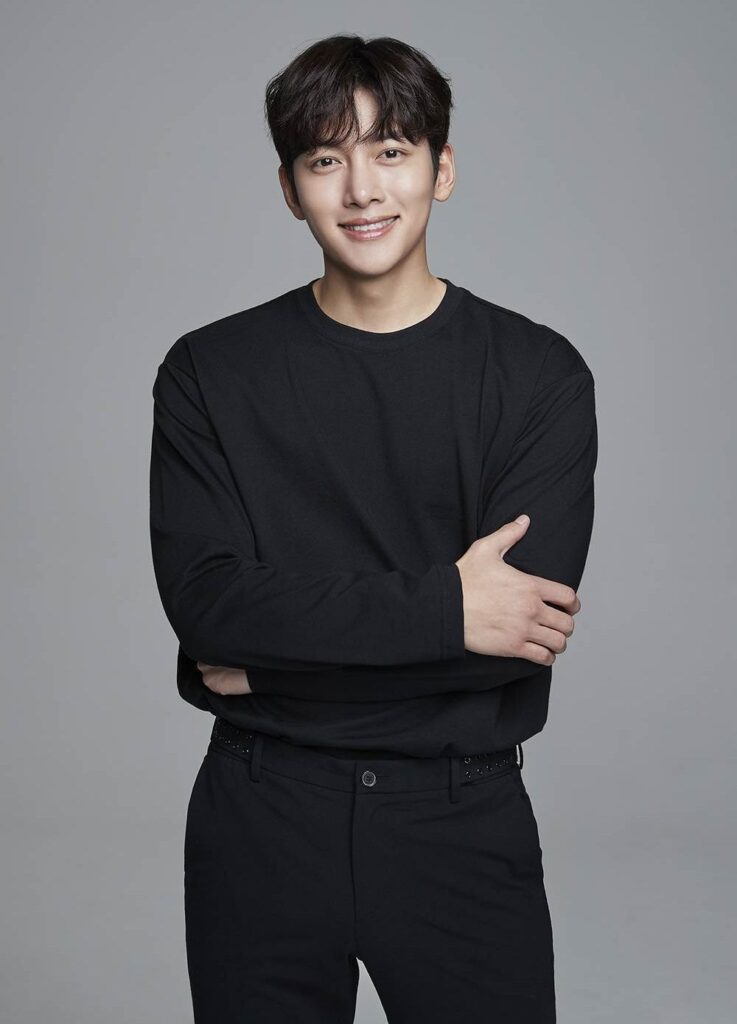 Showcasing the timeless appeal of sleek monochrome minimalism, Ji Chang Wook matches an understated black long-sleeve crewneck with sharp tailored trousers for a clean, versatile luxury aesthetic.