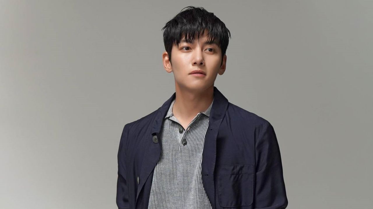 Ji Chang Wook delivers effortless smart-casual sophistication by pairing a relaxed navy chore jacket over a subtle striped polo shirt, presenting a refined layering formula for modern men's style.