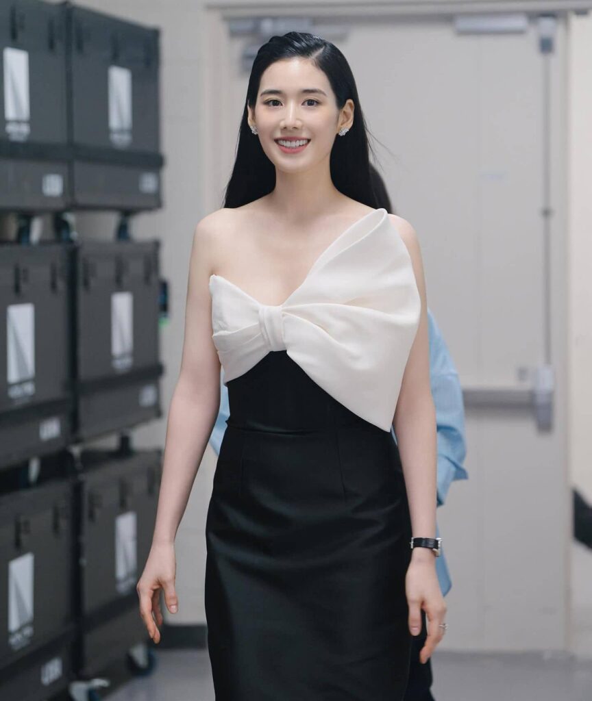 Making a striking statement in modern monochrome, Jung Eun Chae elevates classic evening wear with a sleek black tailored column dress accentuated by an architectural oversized white bow.