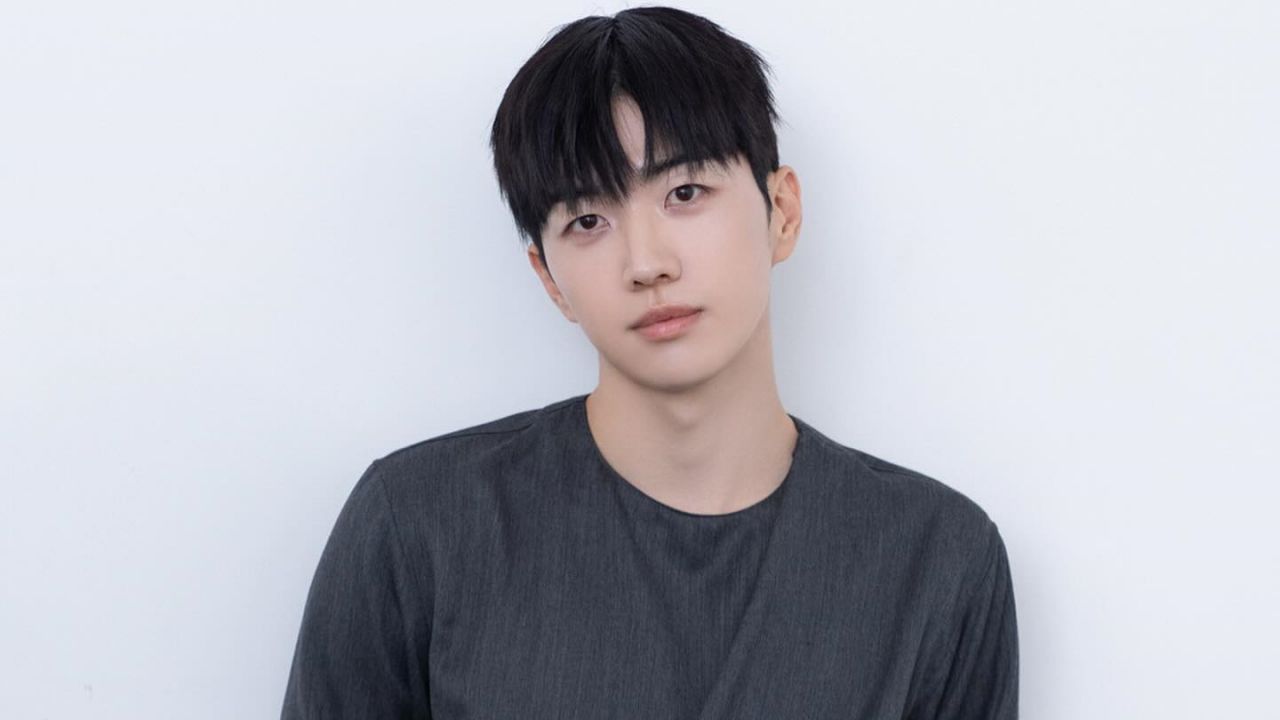 Kang Hoon effortlessly channels understated luxury in a minimalist heather-gray crewneck that emphasizes clean silhouettes and modern, refined simplicity.