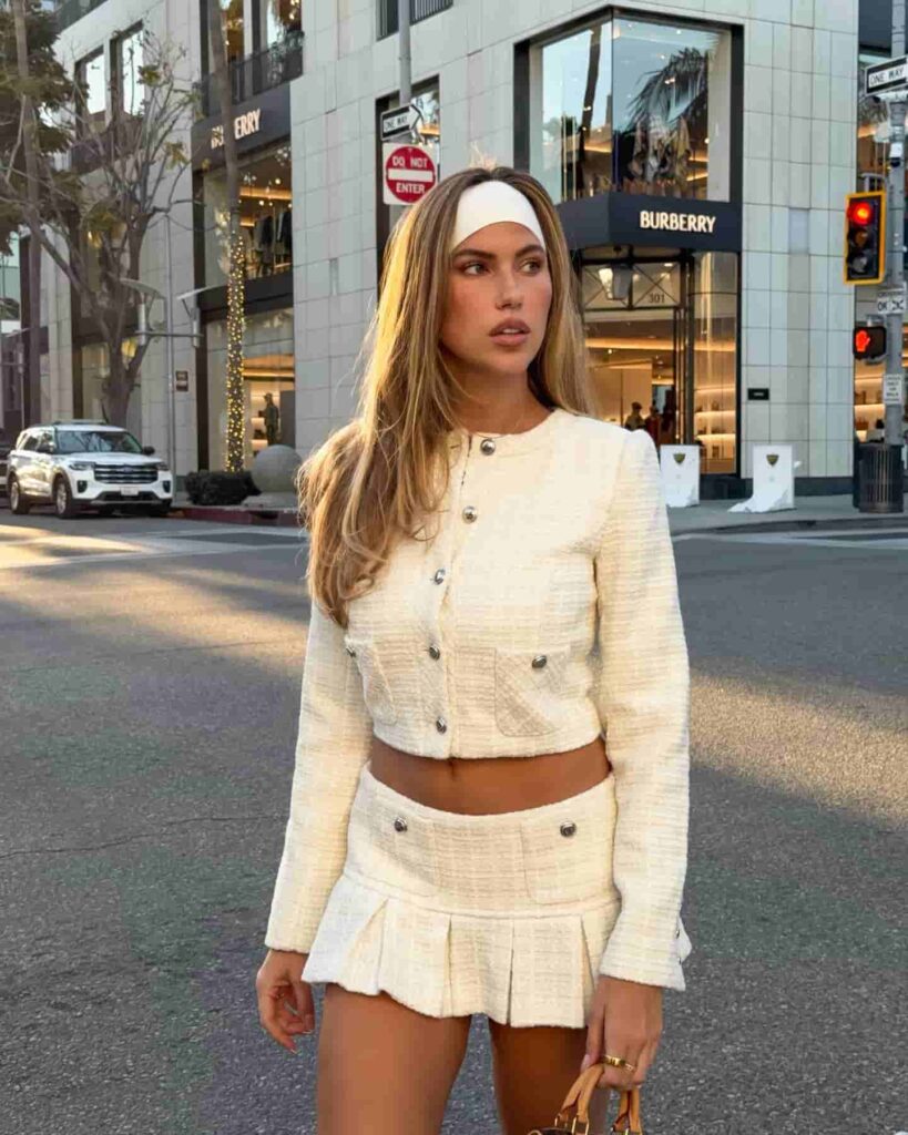 Channeling a sophisticated vintage aesthetic, Kara Del Toro elevates her city street style in a textured cream tweed two-piece set, flawlessly accessorized with a retro white headband.