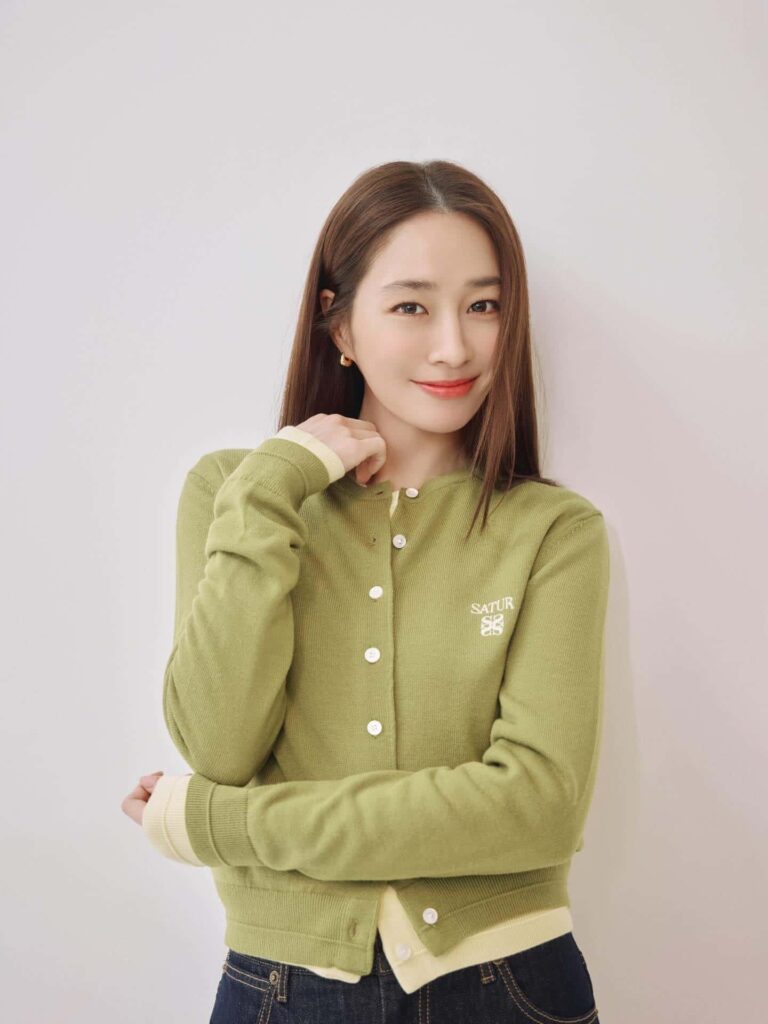 Highlighting the season's top knitwear trends, Lee Min Jung models a sophisticated olive green button-up cardigan flawlessly paired with dark denim jeans for a chic, modern casual outfit.