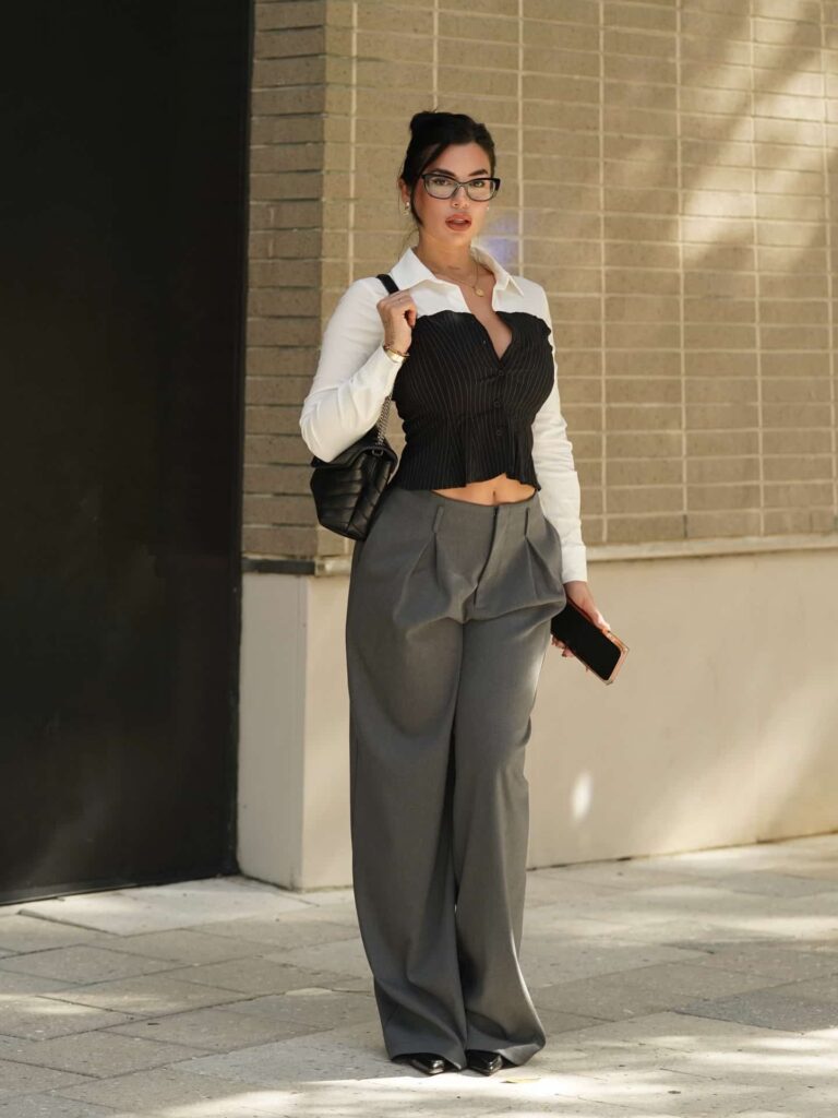 Channeling contemporary power dressing, Luchi Del Mar effortlessly elevates modern street style with high-waisted pleated trousers, a structured two-tone corset shirt, and a classic quilted leather shoulder bag.