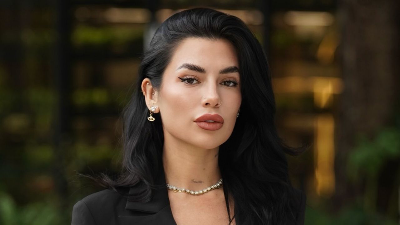 Luchi Del Mar showcases refined minimalism by pairing a tailored black blazer with an elegant pearl choker and subtle gold accents for a timeless, high-end beauty statement.