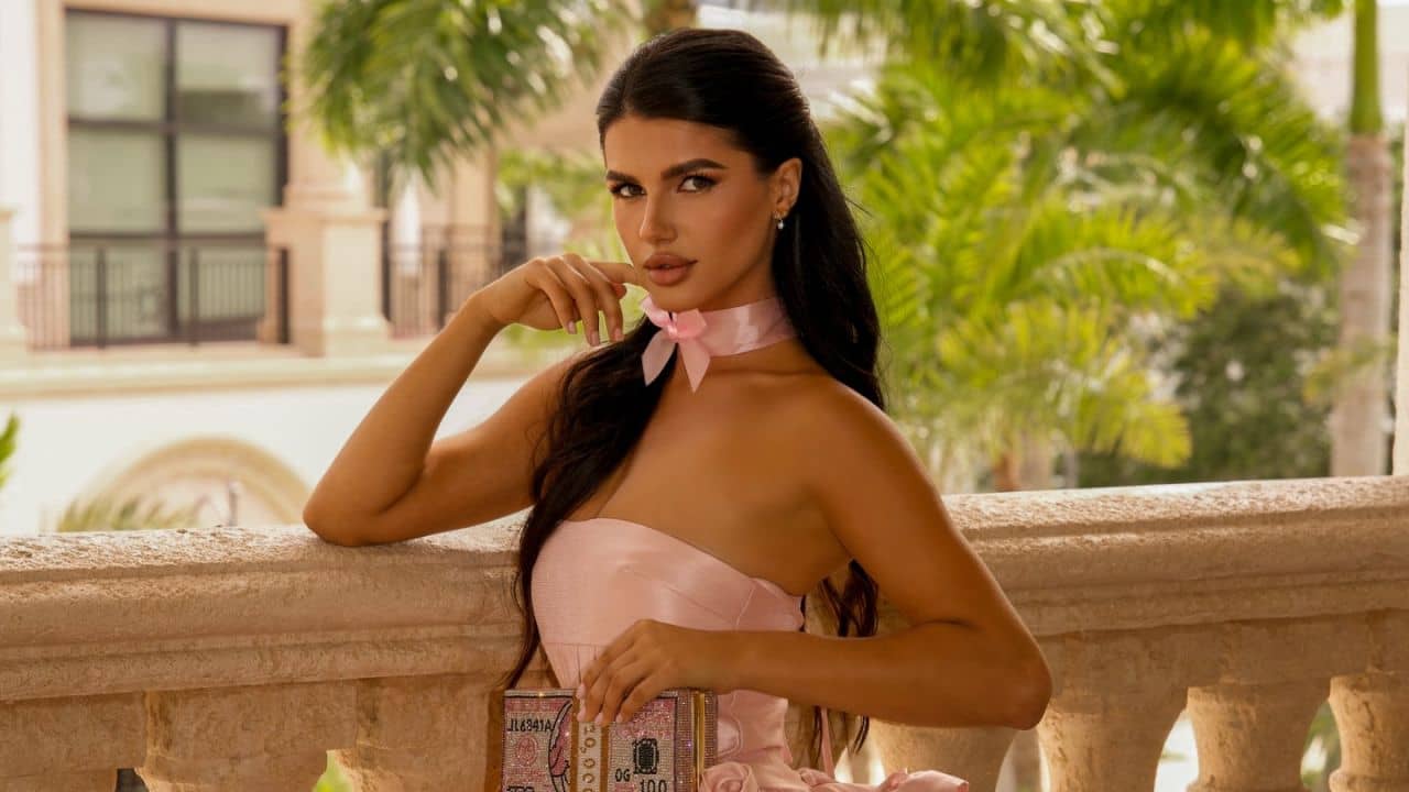 Sofiia Ostrovska channels modern glamour in a structured blush-pink satin corset dress, elevated by a matching silk choker and an eye-catching crystal-embellished statement clutch.